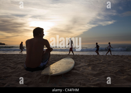 Man sitting on beach with surfboard. Bondi Beach, Sydney, New South Wales, Australia Banque D'Images