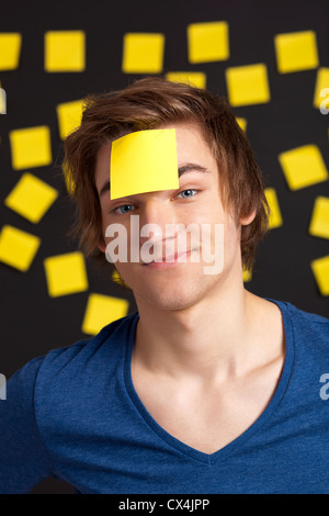 Happy student avec un rappel sur la tête, et avec plus de notes papier jaune à l'arrière-plan Banque D'Images