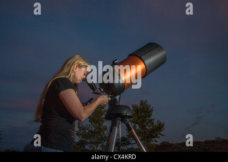 Une jeune femme astronome amateur utilise un catadioptic 2,000mm télescope pour regarder les étoiles sur une soirée à Orange County, CA. Banque D'Images