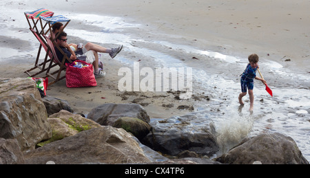 Les parents surveillent leur garçon jouer sur la plage. Banque D'Images