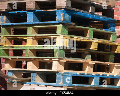 Les palettes en bois en différentes couleurs empilés après utilisation, certains noms d'entreprise peut être vu Banque D'Images