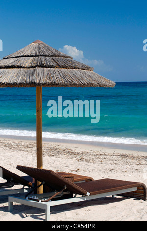 Chaises de plage vue sous un parapluie à rayures beige, seul sur un quartier calme, propre, sunny beach. Banque D'Images