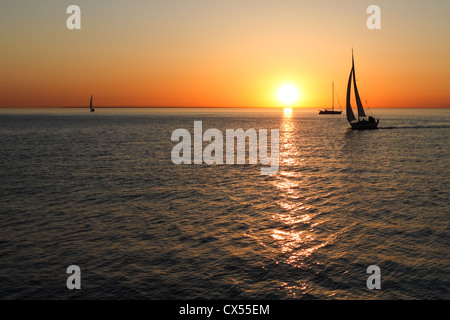 Or les silhouettes de bateaux en mer au coucher du soleil Banque D'Images