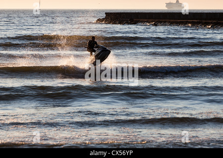 Jeune mec en croisière dans la mer Baltique, sur un jet-ski au coucher du soleil Banque D'Images