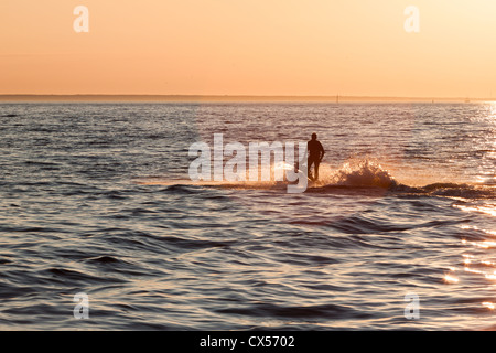 Jeune mec en croisière dans la mer Baltique, sur un jet-ski au coucher du soleil Banque D'Images