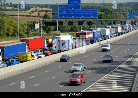 Trafic stationnaire engorgée sur quatre aiguilles lane autoroute M25 avec des aiguilles d'une route permettant de se déplacer librement (certaines plaques obscurci) Banque D'Images