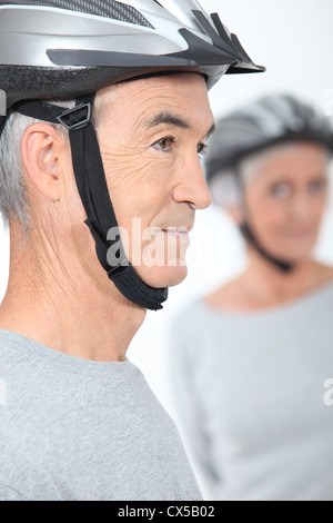 Couple de personnes âgées avec les casques de vélo Banque D'Images