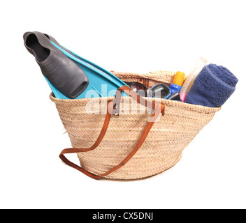 Panier en osier avec serviette, lunettes, tuba, palmes et lait solaire Banque D'Images