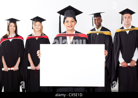 Diplômé indien féminin holding white board avec ses camarades en arrière-plan Banque D'Images