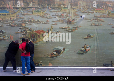 Les hommes montres caméra CCTV peeling l'arrière-plan de Canaletto au xviiie siècle, la peinture de l'Éternel Show du maire, régates à la gare de London Bridge. Les 30 mètres de long travail de l'art est placé sur un mur temporaire à l'entrée de station récemment rénové. L'image est une reproduction de la Tamise de Canaletto sur Lord Mayor's Day, reproduit à cette échelle les navetteurs et les touristes sont en mesure d'admirer le détail de la célèbre peinture représentant la vie animée de la Lord Mayor's Show vu de procession de la rivière avant 1752 Bankside. Banque D'Images