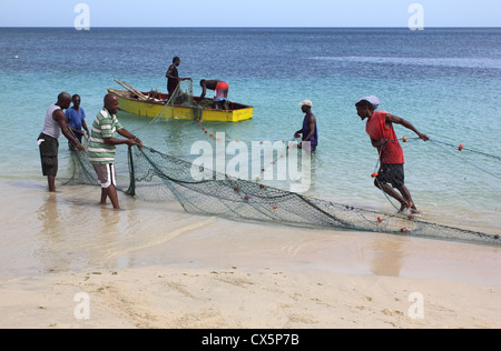 Les pêcheurs des Caraïbes Contrôle et remise à zéro leurs filets dans leur bateau, plage de Grand'Anse, La Grenade. West Indies. Banque D'Images