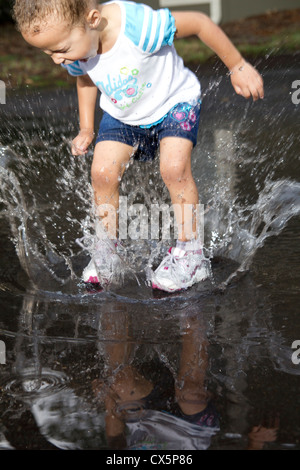 Jeune fille sautant dans la flaque. Banque D'Images