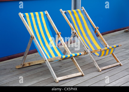 Deux rayures bleu et jaune vide transats sur Boscombe Pier en Août Banque D'Images