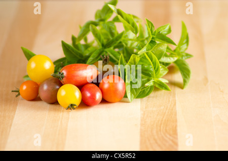 Tomates fraîches et basilic sur une planche à découper en bois Banque D'Images