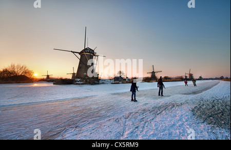 Patineurs sur un canal gelé col old dutch windmills près de la zone de Pays-bas Kinderdijk Banque D'Images