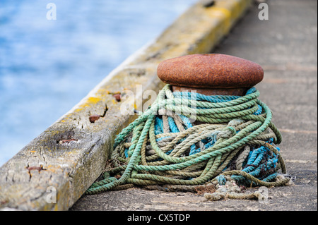 Amarrage colorés warps lâchement autour de la plaie un bollard maritime sur une jetée de la mer du Nord au nord de l'Angleterre. Banque D'Images