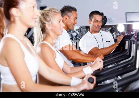 Les gens en vélo de remise en forme Salle de sport avec un entraîneur personnel Banque D'Images