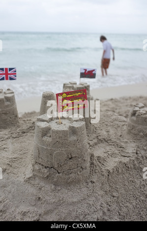 Châteaux de sable d'un enfant avec le drapeau dans le premier plan avec le gallois et l'Union jack drapeaux à la recherche sur de derrière Banque D'Images