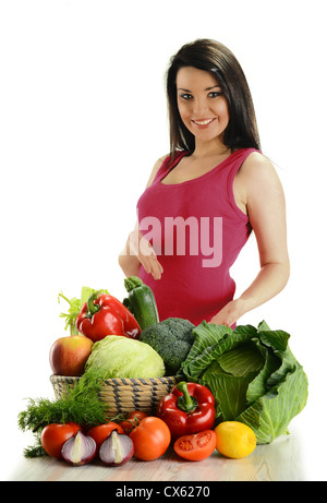 Young smiling woman standing à la table avec variété de légumes crus dans des paniers en osier isolated on white Banque D'Images