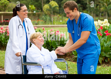 Friendly doctor récupération de souhaits senior patient in wheelchair outdoors Banque D'Images