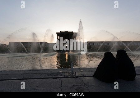 2 femmes couverte à côté d'une fontaine en face du palais Ali Qapu sur l'Naqsh-e Jahan Square, ou place Imam, à Isfahan, Iran Banque D'Images