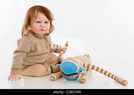 Une petite fille assise avec un jouet en peluche Banque D'Images