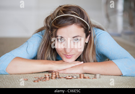 Une femme couchée sur un étage avec des piles de US coins Banque D'Images
