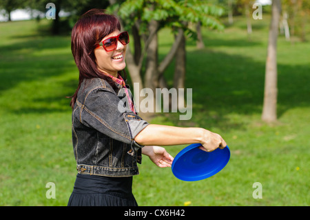 Young woman having fun with frisbee dans le parkin journée ensoleillée. Banque D'Images