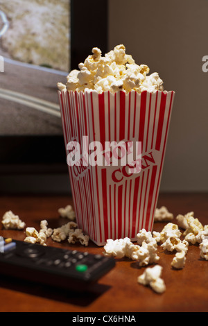 Un carton à rayures rouges de popcorn sur une table en face d'une télévision écran plat Banque D'Images