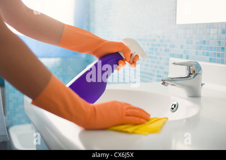 Femme petits travaux dans salle de bains à la maison, nettoyage évier et robinet avec détergent spray. Portrait Banque D'Images