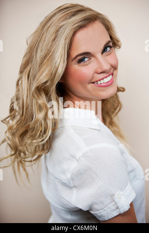 Une jeune femme blonde à la Par-dessus son épaule, smiling Banque D'Images