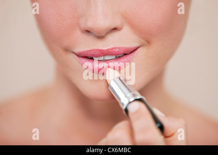 A young woman applying lipstick, montrant la partie inférieure de la face Banque D'Images