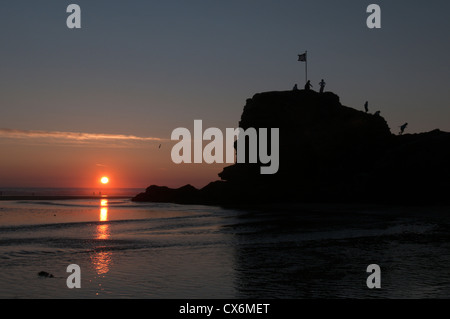 Les gens au-dessus de chapelle Rock, plage de Perran, Broad Oak, Cornwall, UK. Le coucher du soleil. Juillet. À marée basse. Banque D'Images