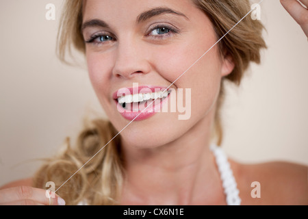Une jeune femme soie dentaire Les dents Banque D'Images