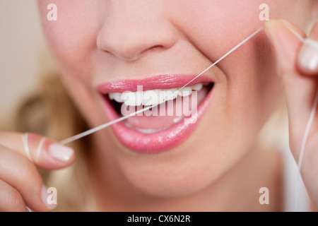 Une jeune femme soie dentaire Les dents, Close up Banque D'Images