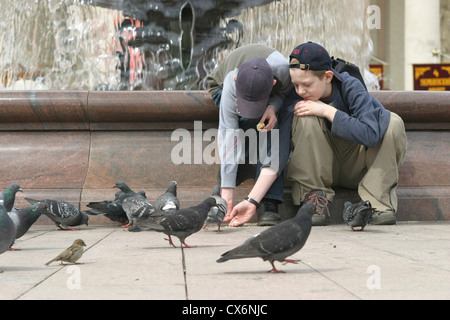 Les garçons nourrir pigeons sur le jour de la Victoire en face du Théâtre Bolchoï à Moscou, Russie Banque D'Images