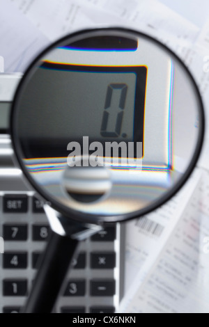 Une loupe magnifier un zéro sur une calculatrice sur le dessus de la paperasse Banque D'Images