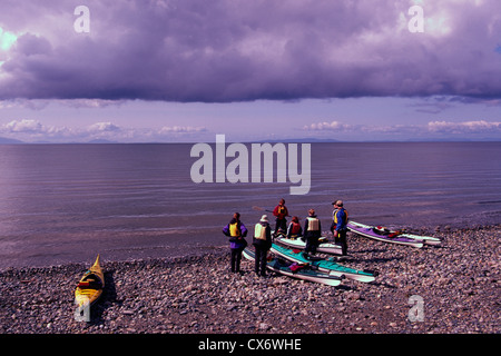 Les kayakistes avec des kayaks sur une plage de l'océan Pacifique en contemplant les nuages sombres approchent Banque D'Images