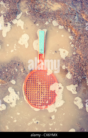 Raquette de tennis jouet en plastique se trouvant dans l'eau flaque Banque D'Images