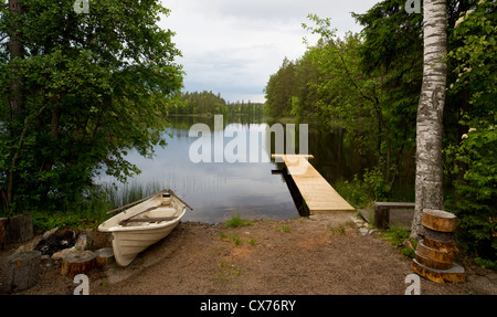 Barque / skiff / canot , plage et jetée en bois sur un petit lac , Finlande Banque D'Images