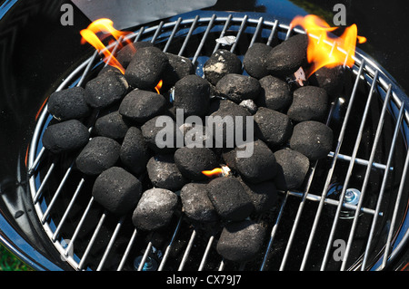 Des briquettes de charbon de bois brûlant dans un petit barbecue mobile Banque D'Images