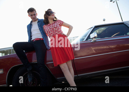 Un endroit frais, rockabilly couple appuyé contre une voiture ancienne Banque D'Images