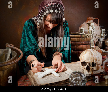 Gypsy Voodoo mettre des aiguilles dans une poupée de l'incantation d'un sort ou une malédiction sur elle (le livre est de 300 ans, pas de problèmes de droits d'auteur) Banque D'Images