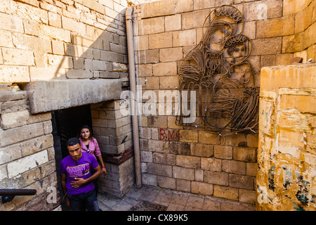 Jeune couple copte sortant d'un passage souterrain par une image vierge Marie en copte du Caire, Égypte. Banque D'Images