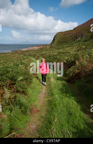 Vue de face d'une femme personne marchant à travers la campagne portant des vêtements imperméables et un sac à dos Banque D'Images