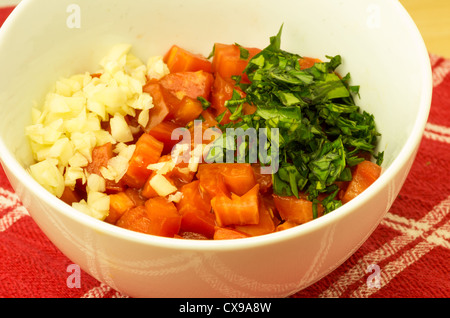 Bol blanc avec des morceaux de tomate basilic oignon ingrédients Banque D'Images