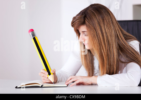 Businesswoman prenant des notes sur son bloc-notes avec un crayon géant Banque D'Images