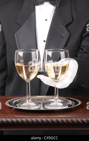 Close up d'un serveur avec deux verres de Chardonnay sur un plateau d'argent et plaqués bois format vertical de la table Banque D'Images