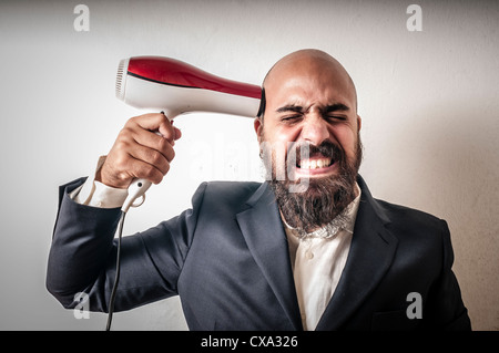 Homme chauve avec un sèche-cheveux peur sur fond blanc Banque D'Images