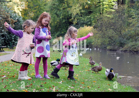 Trois jeunes filles se nourrir du pain pour les canards sur une berge, dans les collines de Hubbard en automne. Banque D'Images